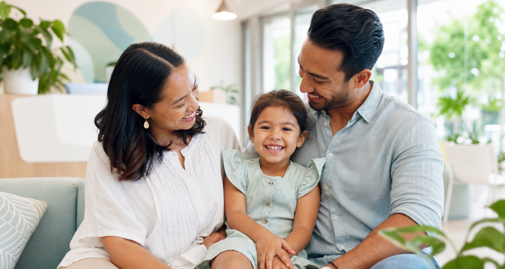 Smiling child relaxing with both parents in a bright welcoming dental clinic