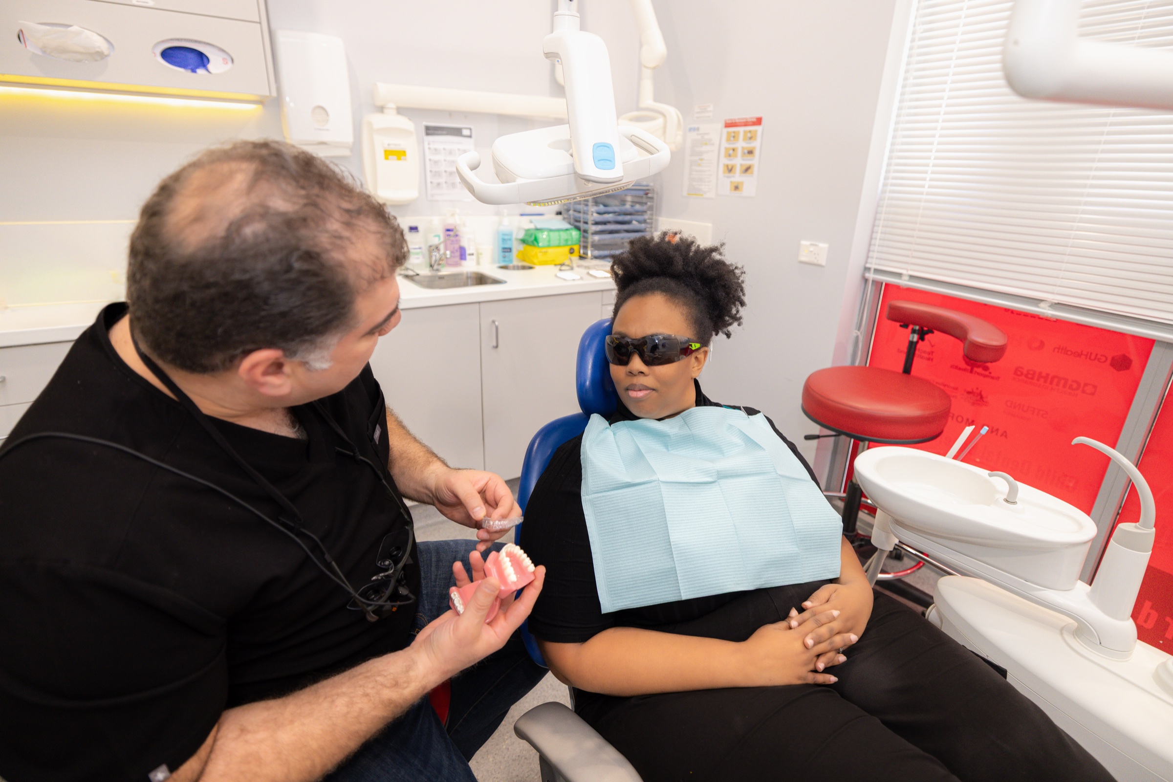 Patient wearing protective glasses seated in the dental chair with Dr Ehsan Alekajbaf