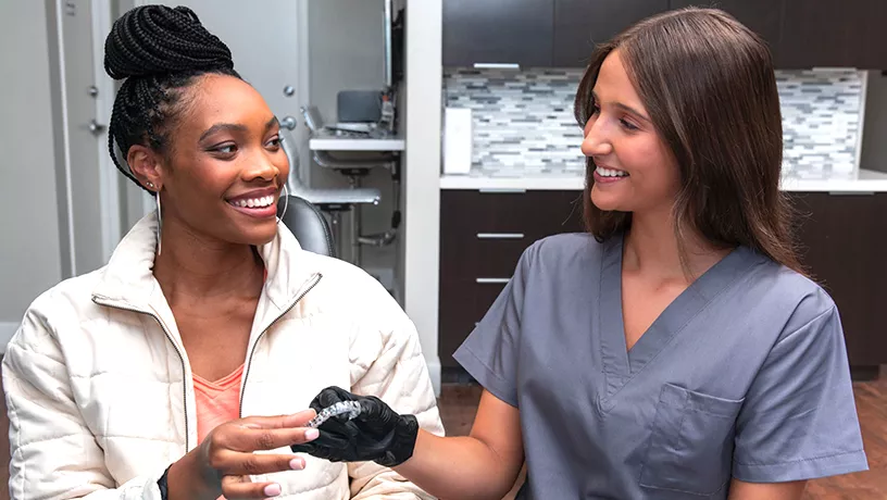 A patient and clinician holding clear aligners during a consultation
