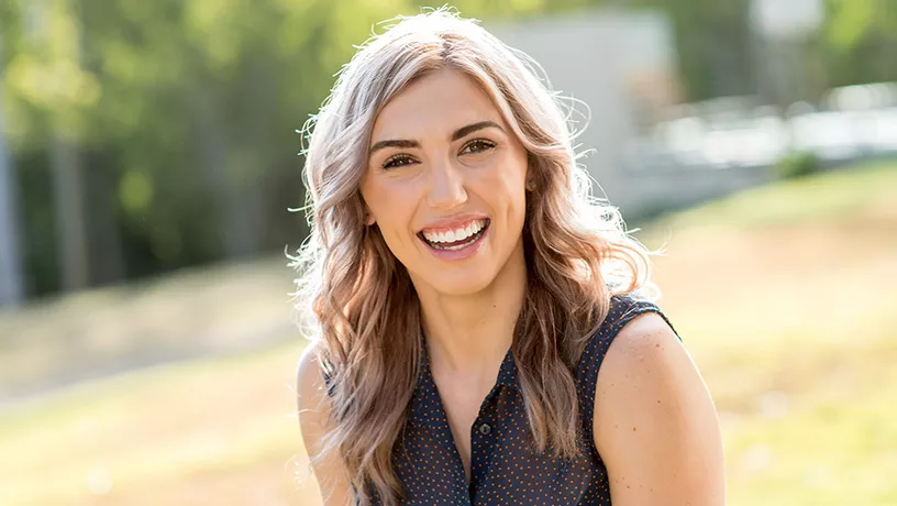 A smiling person outdoors featured in official Spark Clear Aligners media